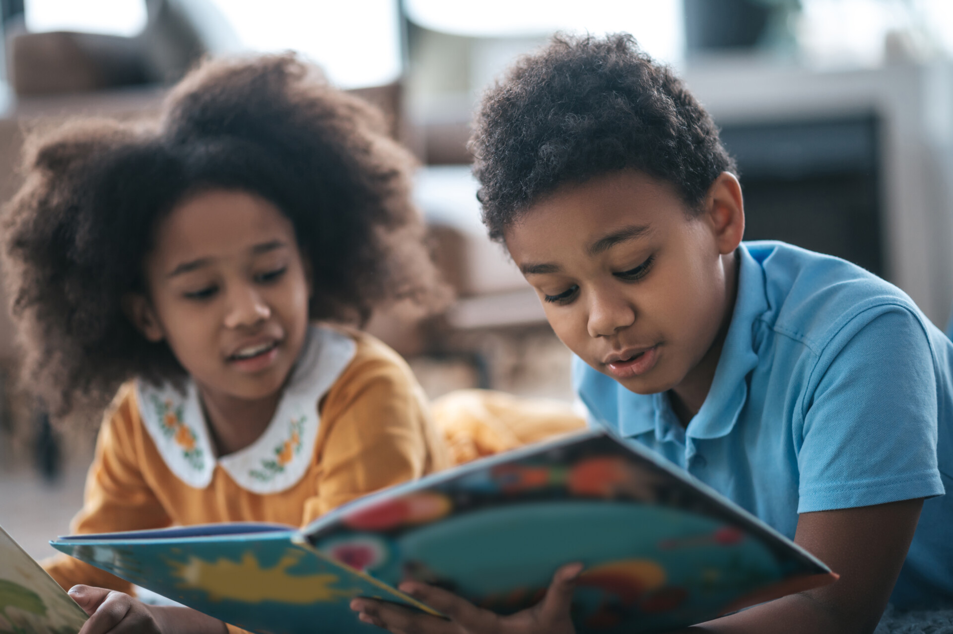 Two children lying on the floor and reading a book