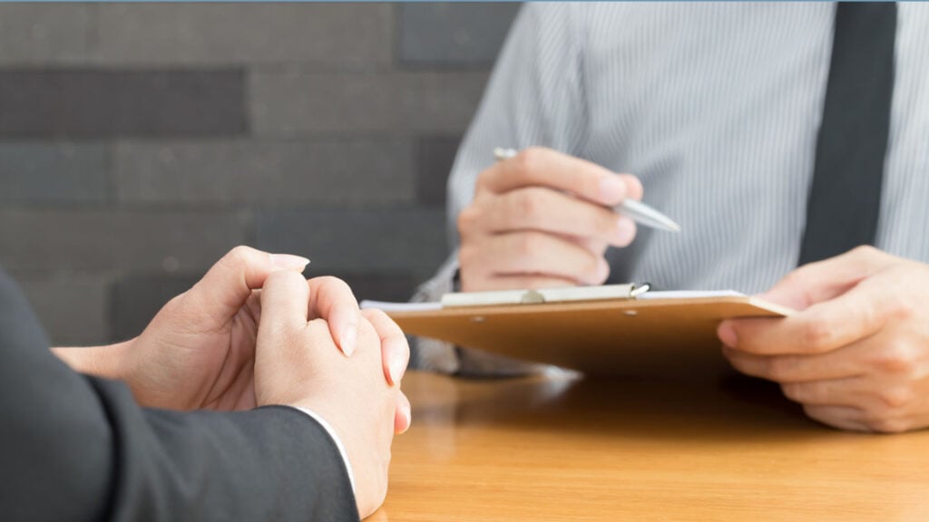 someone holding a clipboard and pen, asking questions to someone else.