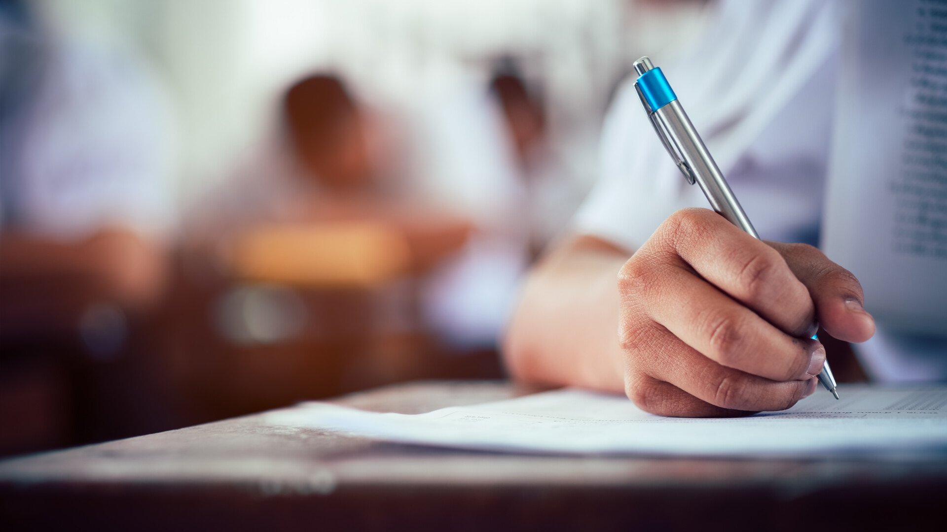 close up of a student's hand writing on a paper in an exam