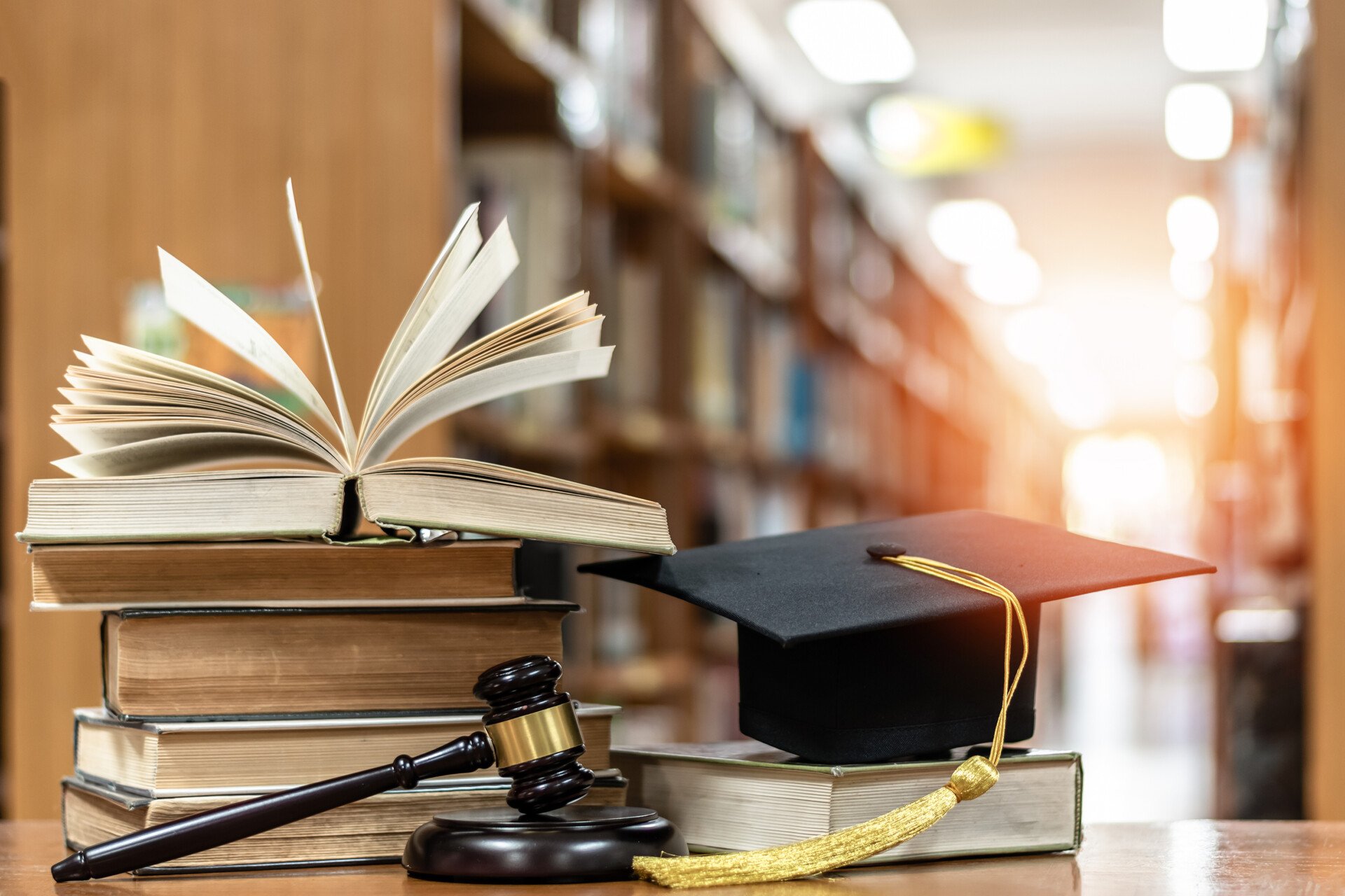 A graduation cap, judges gavel, and a pile of books on a table