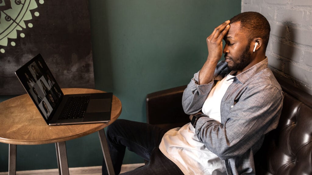 a man on a work video conference with his head in his hand