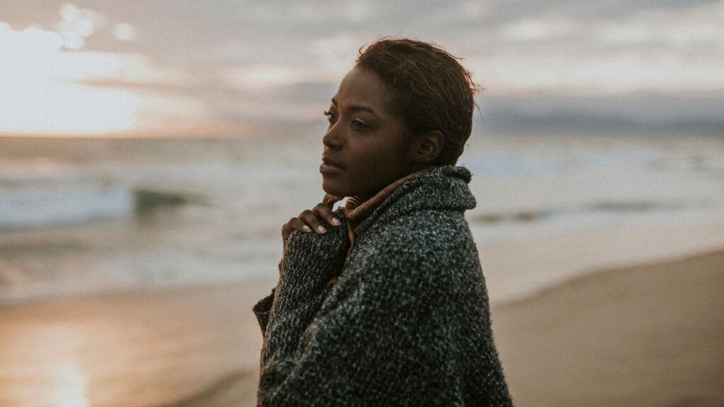 a woman stood alone on a beach, peaceful