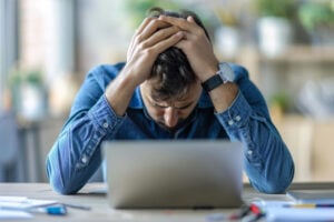 A stressed professional man seated at his desk in the office, depicting an overwhelmed businessman or a fatigued student under pressure.