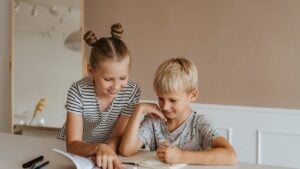 An older child helping a younger child with their homework