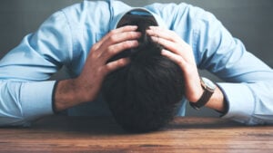 a man with his head on a table, hands on his head